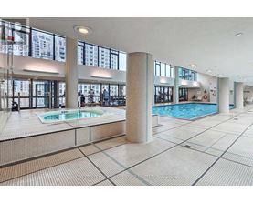 A large indoor swimming pool with a tiled floor and a glass wall.