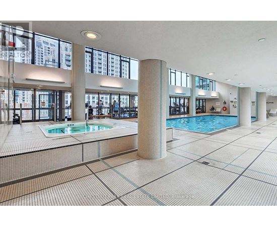 A large indoor swimming pool with a tiled floor and a glass wall.