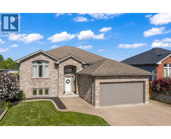 A house with a grey garage door and a white door with a wreath on it.