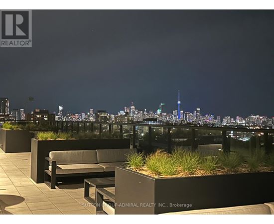 A rooftop patio with a view of the city skyline at night.