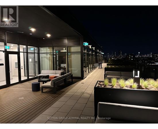 A rooftop patio with a couch and a view of the city at night.