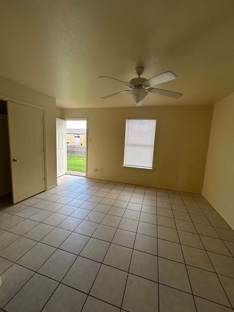 A room with a ceiling fan and tiled floor.