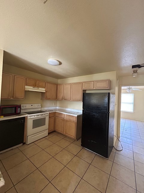 A kitchen with black appliances and brown cabinets.