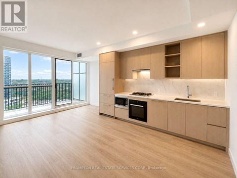 A kitchen with wooden floors and a large window overlooking a balcony.