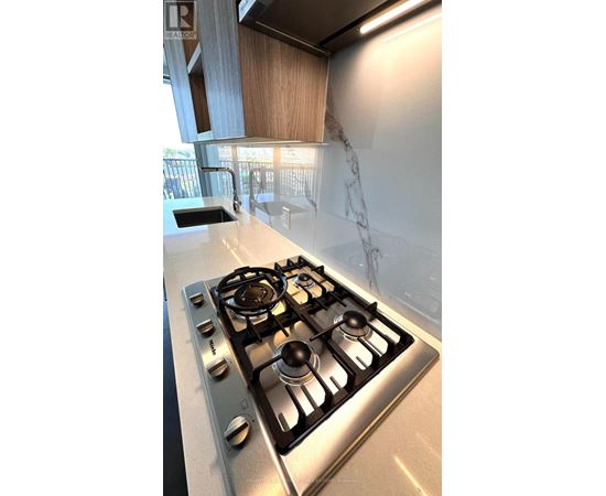 A stainless steel gas stove with four burners is in a kitchen.