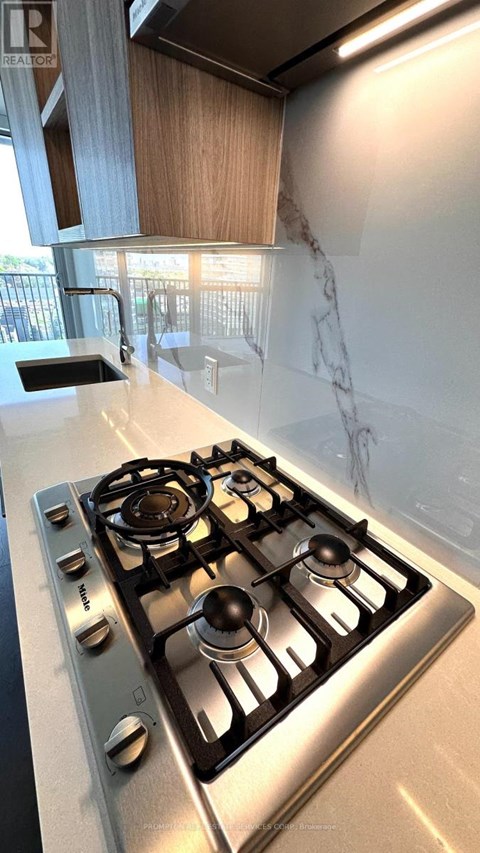 A stainless steel gas stove with four burners is in a kitchen.