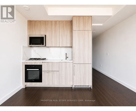 A kitchen with wooden cabinets and a black microwave.
