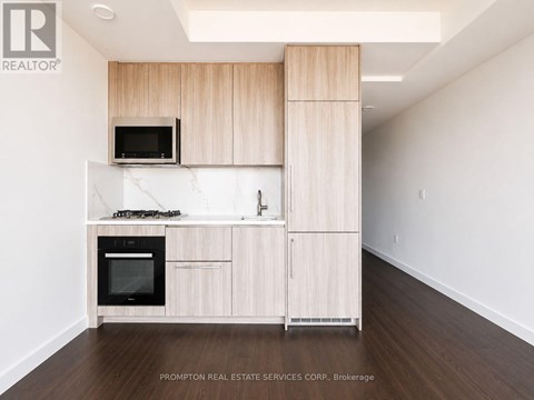 A kitchen with wooden cabinets and a black microwave.