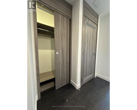 A wood paneled room with a door open to a bedroom.