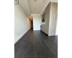 A long hallway with wood floors and white walls.
