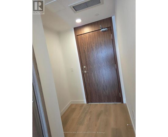 A wooden door in a hallway with a light on the ceiling.