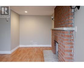 A room with a brick fireplace and wooden flooring.