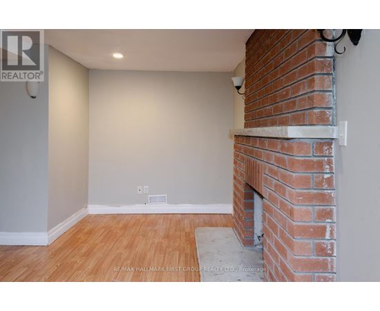 A room with a brick fireplace and wooden flooring.