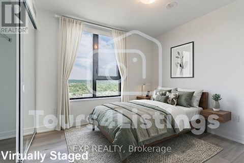 A bedroom with a large bed and a window overlooking the city.