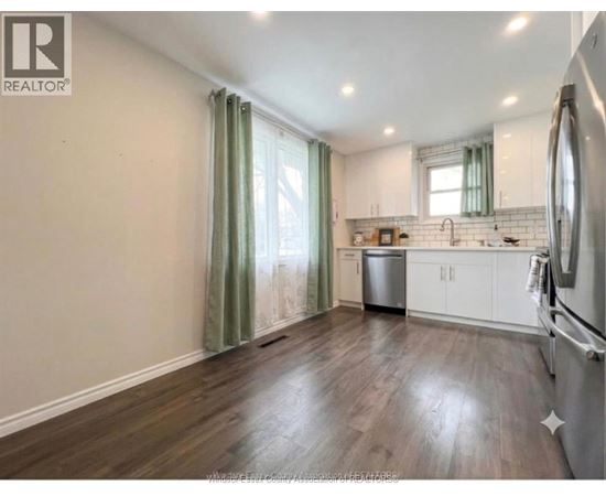 A kitchen with wooden floors and white cabinets.