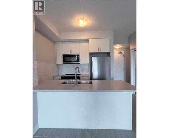 A kitchen with a white counter top and stainless steel appliances.