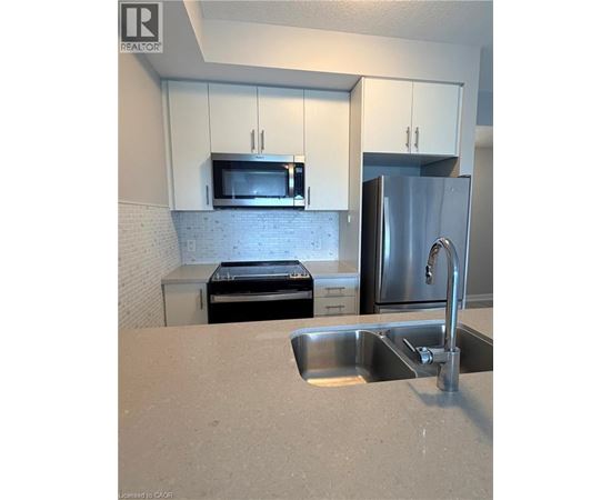 A kitchen with a stainless steel refrigerator, microwave, and oven.