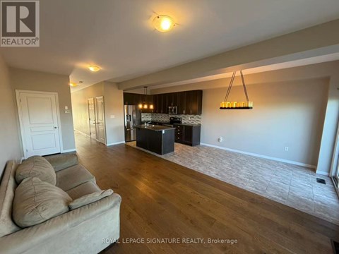 A living room with a couch and a kitchen area in the background.