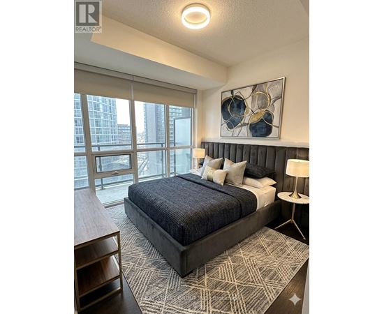 A bedroom with a large bed and a painting on the wall.