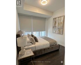 A bedroom with a bed, nightstand, and a painting on the wall.