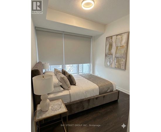 A bedroom with a bed, nightstand, and a painting on the wall.