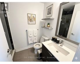A bathroom with a toilet, sink, and mirror.