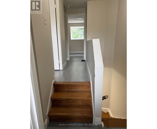 A hallway with a staircase leading to a bedroom.