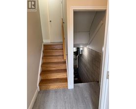 A hallway with a staircase and a doorway leading to a kitchen.