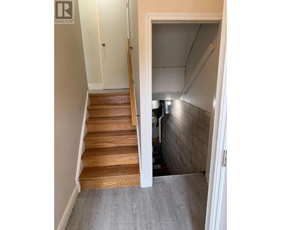 A hallway with a staircase and a doorway leading to a kitchen.