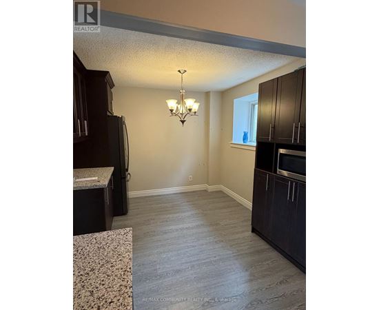 A kitchen with dark wood cabinets and a granite countertop.