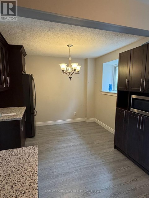 A kitchen with dark wood cabinets and a granite countertop.