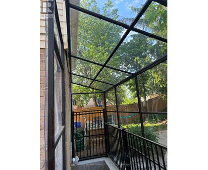 A balcony with a black railing and a view of a backyard.