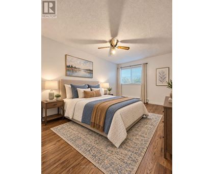 A bedroom with a bed, a ceiling fan, and a painting on the wall.