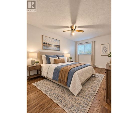 A bedroom with a bed, a ceiling fan, and a painting on the wall.