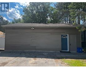 A garage with a blue door is surrounded by trees.
