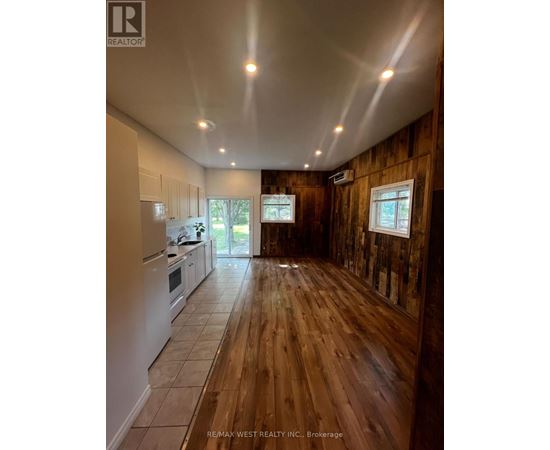 A wood panelled room with a kitchen area to the left.