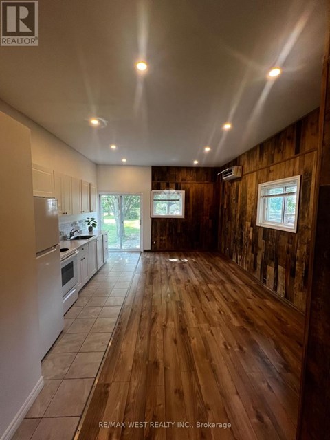 A wood panelled room with a kitchen area to the left.