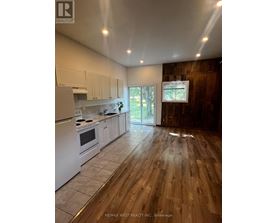 A kitchen with white appliances and wooden floors.