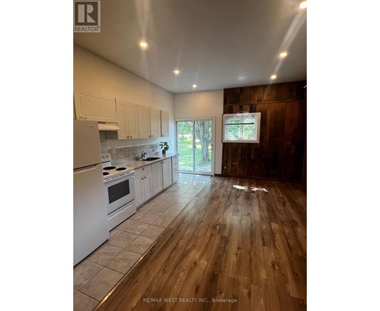 A kitchen with white appliances and wooden floors.