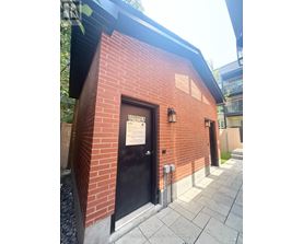 A small red brick building with a black door and a sign on it.