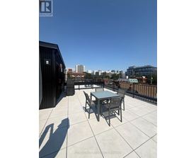 A balcony with a table and chairs overlooking a cityscape.