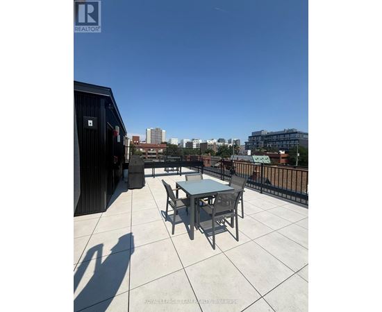 A balcony with a table and chairs overlooking a cityscape.
