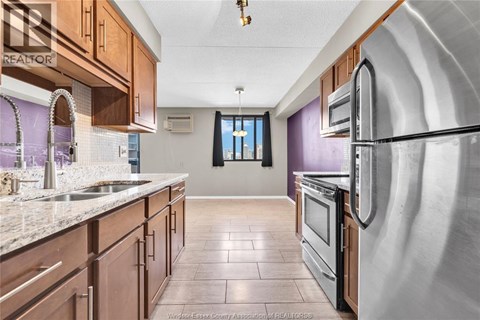 A kitchen with wooden cabinets and a stainless steel refrigerator.