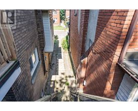 A view of a narrow alley between two buildings with a watermark of "KAMALI GROUP REALTORS".