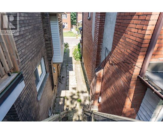 A view of a narrow alley between two buildings with a watermark of "KAMALI GROUP REALTORS".