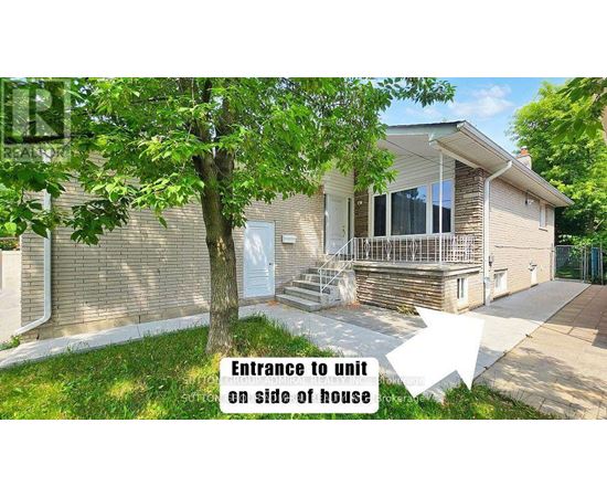 A house with a tree in front and an entrance to a unit on the side of the house.