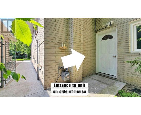 A house with a white door and a sign that says "Entrance to unit on side of house".