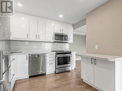 A modern kitchen with white cabinets and stainless steel appliances.