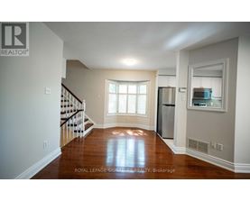 A spacious living room with hardwood floors and a staircase leading to the upper level.