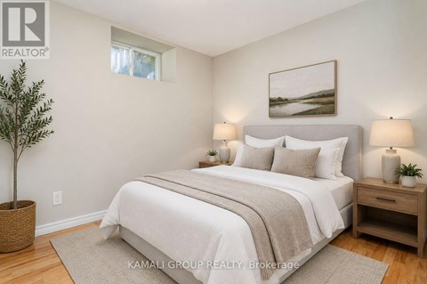 A bedroom with a large bed, a potted plant, and a framed picture on the wall.